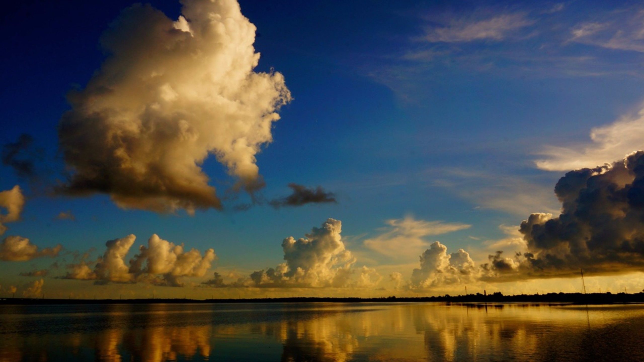 Puffy clouds over a calm lake at sunset